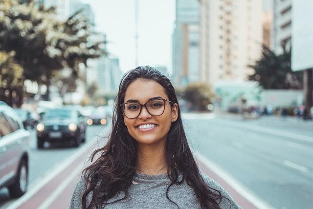 woman of color smiling at camera near a busy city street