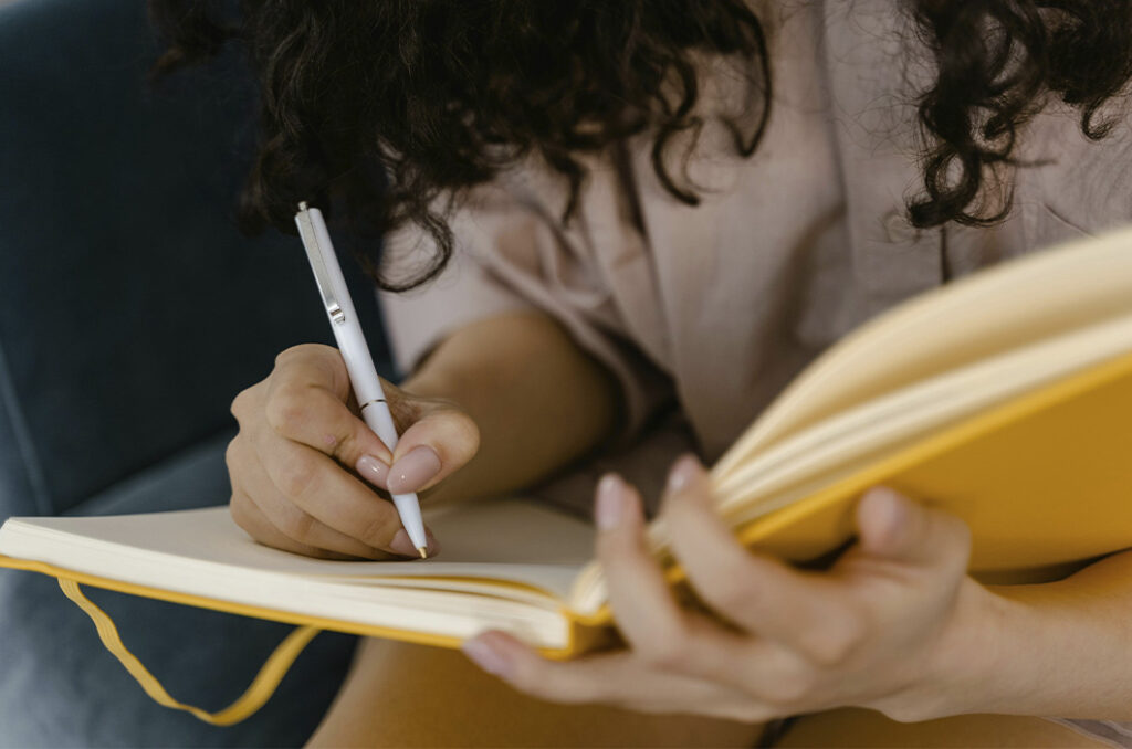 Girl writing on her diary, representing the journey told by our therapist