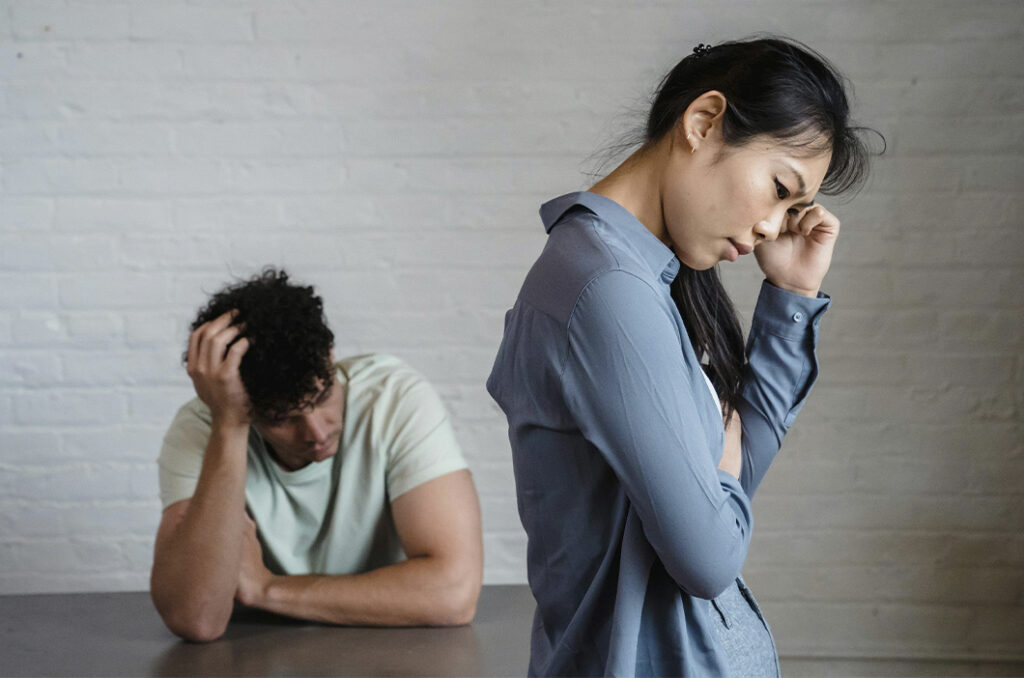 Couple with their backs turned, looking upset and lost, represents how it can be hard to identify the signs of a toxic relationship.