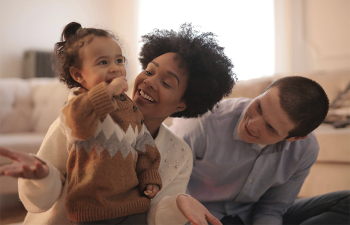 Parents with their baby smiling together, representing our therapist dedication to supporting families and postpartum parents. 