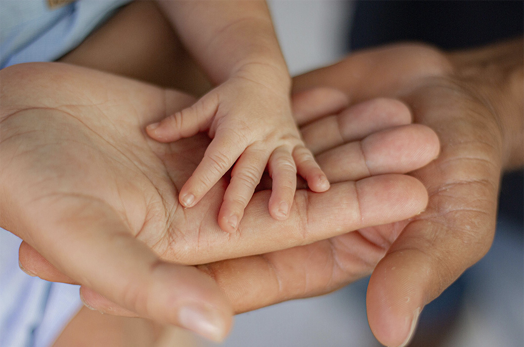 Hands of parents and their baby, representing the journey of our therapist Amanda DeBoy in becoming a counselor.