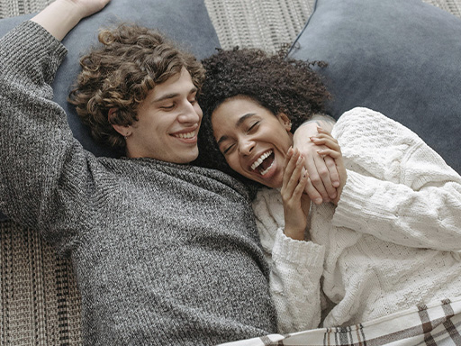 Couple lying together on pillows looking happy and connected, represents how you can heal through affair recovery in Deerfield, IL.