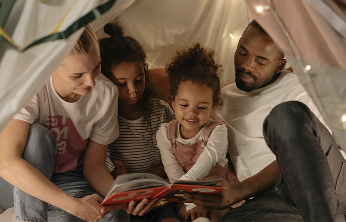 Happy family reading a book together, represents how blended families can invest time and energy into their familyness and make children of divorce a priority.