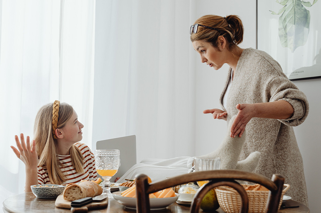Mother and teen daughter arguing at breakfast, represents the effect of a critical mother on a daughter.