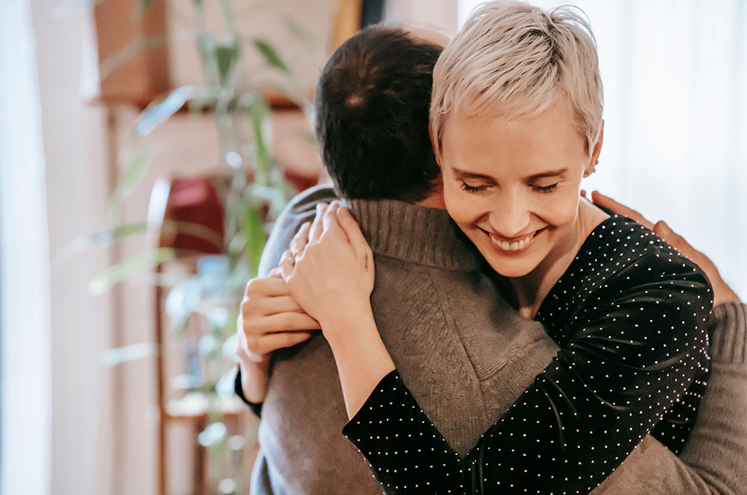 Woman hugging someone and smiling, represents how you can learn strategies to resolve family conflict.