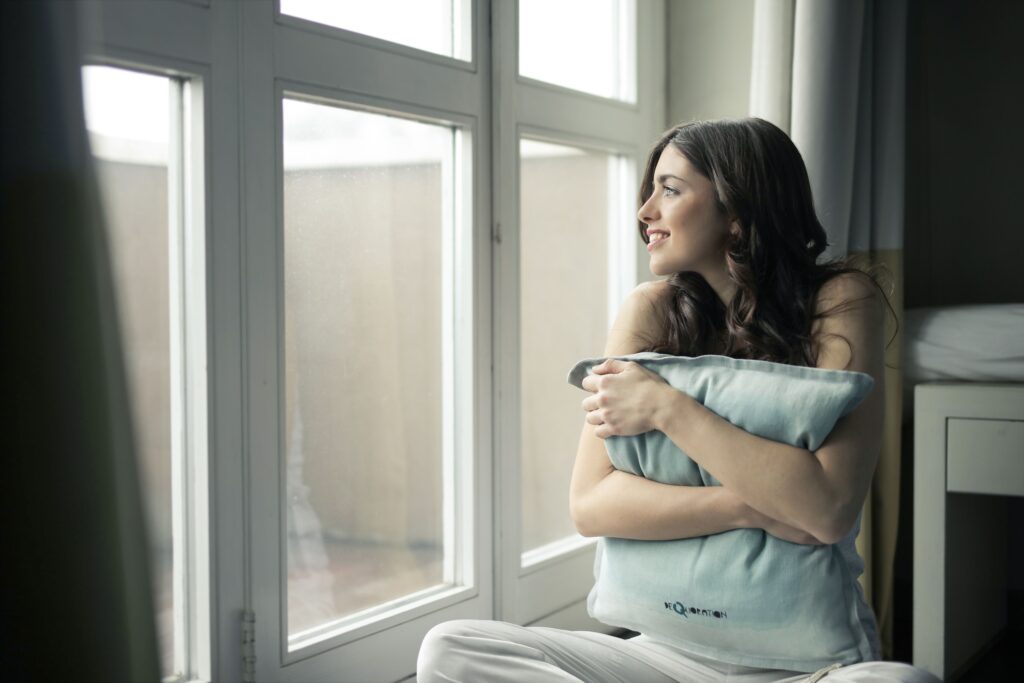 A woman hugging a pillow by a sunny window, taking a quiet breath after a long stretch of intrusive thoughts and second-guessing. Every type of OCD, from contamination fears to relationship doubts, responds to treatment like ERP therapy, and relief is possible. OCD treatment in Deerfield, IL at Ammirati Counseling Group starts with a free phone consultation.