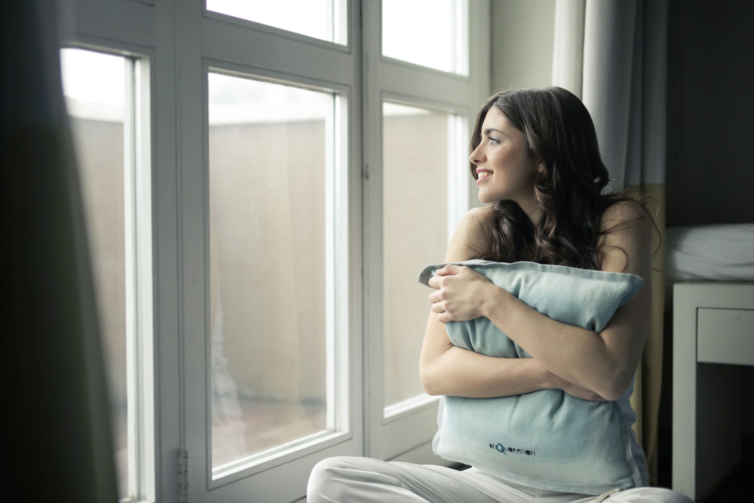 A woman hugging a pillow by a sunny window, taking a quiet breath after a long stretch of intrusive thoughts and second-guessing. Every type of OCD, from contamination fears to relationship doubts, responds to treatment like ERP therapy, and relief is possible. OCD treatment in Deerfield, IL at Ammirati Counseling Group starts with a free phone consultation.