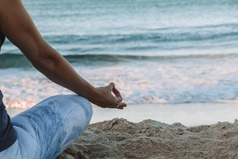 woman meditating at the beach